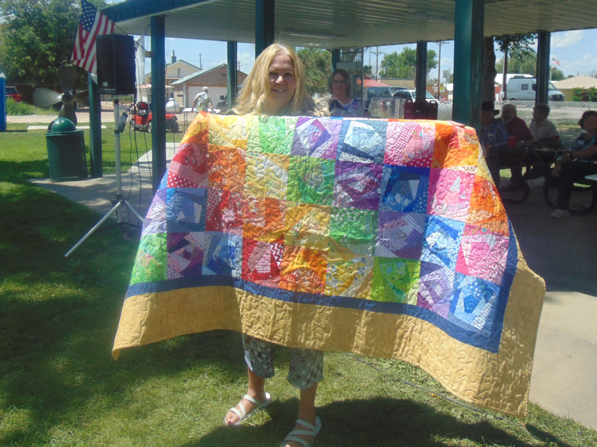 quilt drawing winner, Deane Culp, poses for picture with quilt